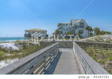 View of beach houses from a wooden boardwalk on a beach at Destin, Florida 94165591