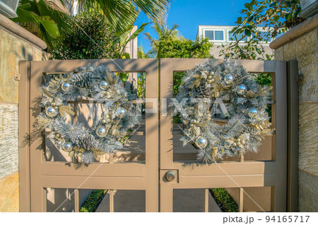 La Jolla, California- Two silver wreaths on a painted beige double gate La Jolla, California- Two silver wreaths on a painted beige double gate 94165717