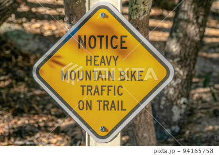 Mount Lemmon, Arizona- Diagonal yellow signage with Notice Heavy Mountain Bike Traffic on Trail 94165758