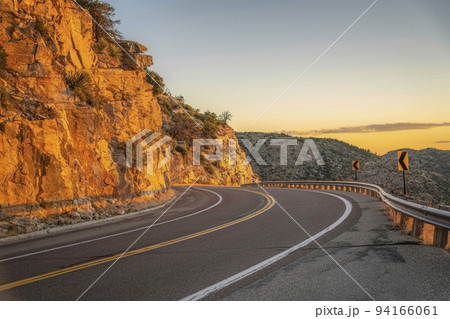 Drive up a winding road along rocky cliffs at sunset in Mount Lemmon Arizona 94166061