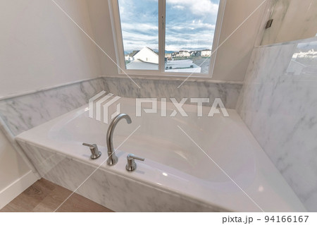 Clean white built in bathtub of home with view of neighborhood houses Clean white built in bathtub of home with view of neighborhood houses 94166167