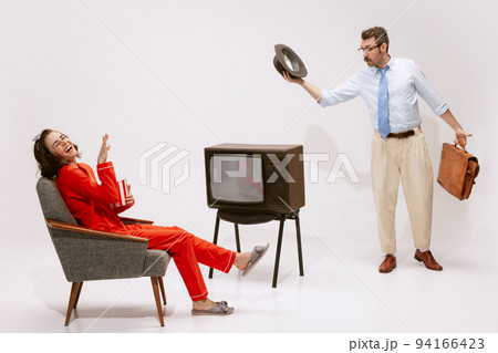 Portrait of couple, woman in pyjama watching TV, eating popcorn, man coming back from work Portrait of couple, woman in pyjama watching TV, eating popcorn, man coming back from work 94166423