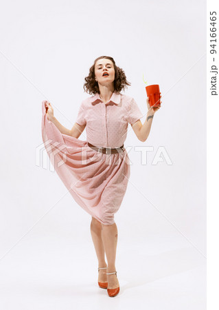 Portrait of beautiful brunette woman posing in pink dress and drinking lemonade isolated over white background 94166465