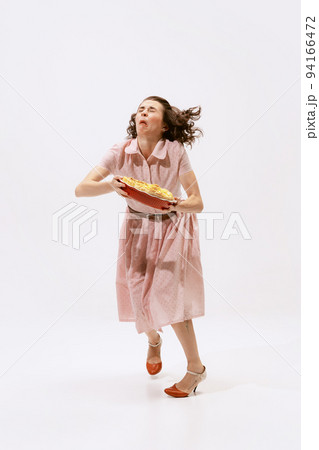 Portrait of emotive woman holding apple pie and falling down isolated over white background. Funny look 94166472