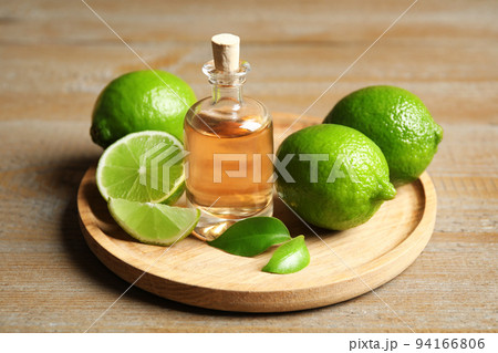 Lime essential oil and citrus fruits on wooden table 94166806