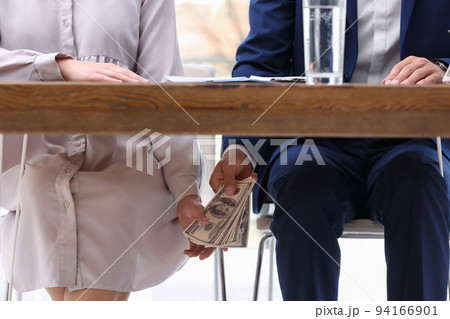 Man giving bribe money under table indoors, closeup Man giving bribe money under table indoors, closeup 94166901