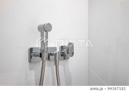 Chromium bidet shower with white tiles in a toilet. Clean and new spray shower. 94167182