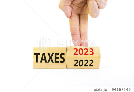 2023 taxes new year symbol. Businessman turns a wooden cube and changes words Taxes 2022 to Taxes 2023. Beautiful white table white background, copy space. Business 2023 taxes new year concept. 94167549