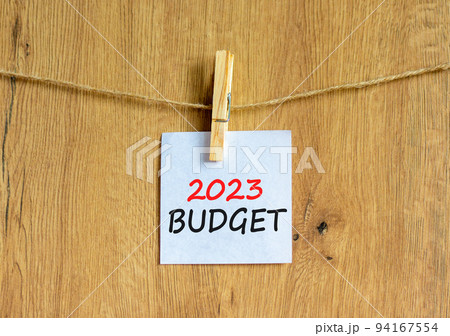 2023 Budget symbol. White paper with words 2023 Budget, clip on wooden clothespin. Beautiful wooden background. Business and 2023 budget concept. Copy space. 2023 Budget symbol. White paper with words 2023 Budget, clip on wooden clothespin. Beautiful wooden background. Business and 2023 budget concept. Copy space. 94167554