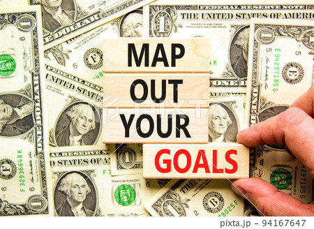 Support and map out your goals symbol. Concept words Map out your goals on wooden blocks on beautiful background from dollar bills. Businessman hand. Business, support and map out your goals concept Support and map out your goals symbol. Concept words Map out your goals on wooden blocks on beautiful background from dollar bills. Businessman hand. Business, support and map out your goals concept 94167647