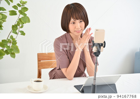 テーブルでネット配信の接続準備をする女性 94167768