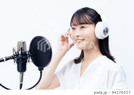 白いヘッドホンを付けて歌う若い女性 94170557