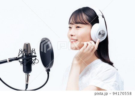白いヘッドホンを付けて歌う若い女性 94170558