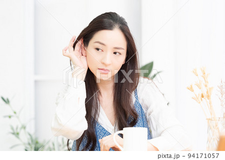 リビングで聞き耳を立てている女性 94171057