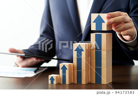 成長戦略を提案するコンサルタントのイメージ。経営データを分析し、計画を立案する。机の上に矢印の描かれ 94173583