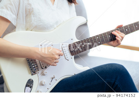 ソファに座りギターを弾く女性（ボディパーツ） 94174152