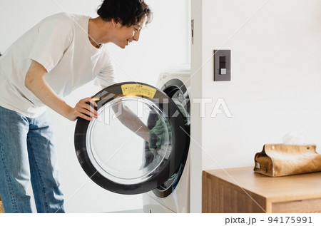 ドラム式洗濯機に洗濯物を入れる男性 ドラム式洗濯機に洗濯物を入れる男性 94175991