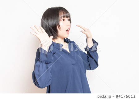 白背景の前で驚いたポーズをする若い女性 94176013