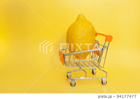 Shopping cart with fruits. bright yellow lemon in a toy shopping cart Shopping cart with fruits. bright yellow lemon in a toy shopping cart 94177477