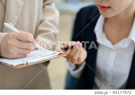 Two Asian businesswomen working and planning a project together. cropped Two Asian businesswomen working and planning a project together. cropped 94177972