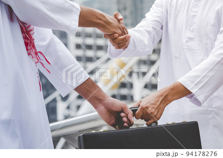 Arab Businessman shaking hands together. Teamwork business partner wear Muslim dress Shake Hands with Partnership Concept. Success UAE diversity people trust make commitment by handshake 94178276