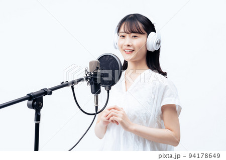 白いヘッドホンを付けて歌う若い女性 94178649
