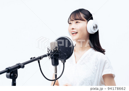 白いヘッドホンを付けて歌う若い女性 94178662
