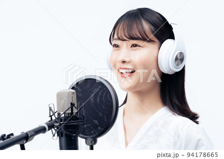 白いヘッドホンを付けて歌う若い女性 94178665