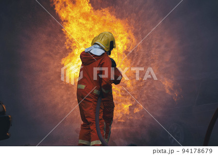 Firefighter fighting with flame using fire hose chemical water foam spray engine. Fireman wear hard hat, body safe suit uniform for protection. Rescue training in fire fighting extinguisher 94178679