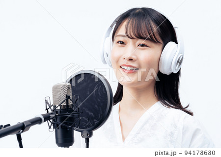 白いヘッドホンを付けて歌う若い女性 94178680