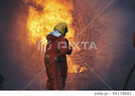 Firefighter Rescue training in fire fighting extinguisher. Firefighter fighting with flame using fire hose chemical water foam spray engine. Fireman wear hard hat, safety suit uniform for protection 94178681