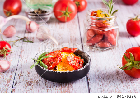 Dried tomatoes with spices and garlic in a bowl and fresh vegetables on the table. Homemade snack 94179236