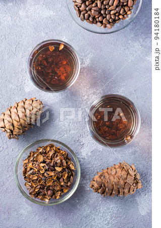 Decoction of pine nut shells in glasses and pine nuts on the table. Alternative medicine. Vertical and top view 94180184