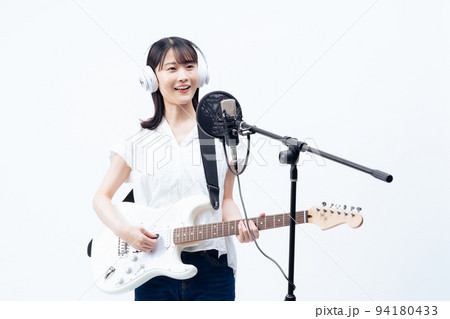 白いヘッドホンを付けて歌う若い女性、エレキギター 白いヘッドホンを付けて歌う若い女性、エレキギター 94180433