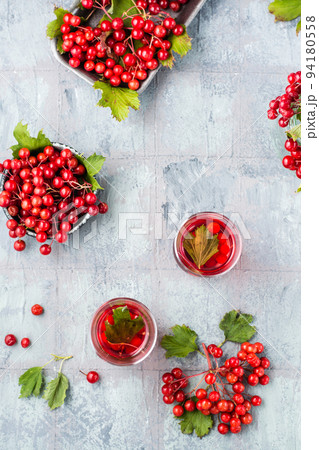 A decoction of ripe viburnum berries in transparent glasses and viburnum berries in bowls next to the table. Alternative medicine, vitamin nutrition and wellness. Top and vertical view A decoction of ripe viburnum berries in transparent glasses and viburnum berries in bowls next to the table. Alternative medicine, vitamin nutrition and wellness. Top and vertical view 94180558