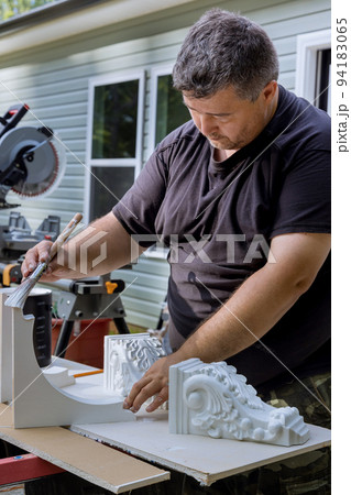 The worker is painting wooden corbels for a kitchen island with the help of a paintbrush 94183065