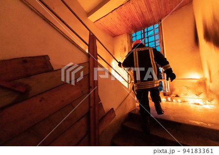 Brave Fireman going upstairs to save and rescue people in a Burning Building. Open fire and flame. Brave Fireman going upstairs to save and rescue people in a Burning Building. Open fire and flame. 94183361