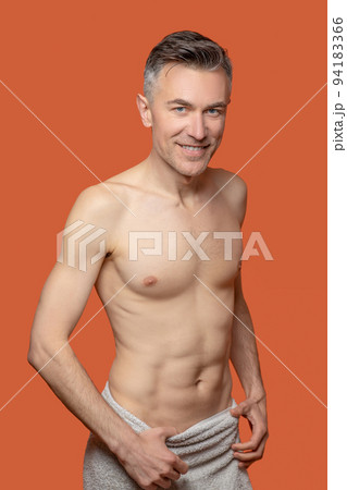 A smiling man with a towel around his thighs 94183366