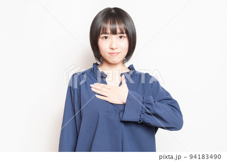 白い背景の前で、胸に手を当てる若い女性 白い背景の前で、胸に手を当てる若い女性 94183490