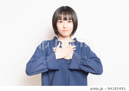白い背景の前で、胸に手を当てる若い女性 94183491