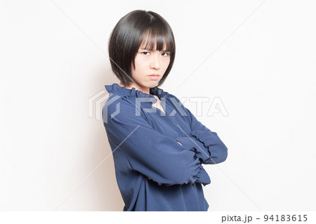 白背景の前に立って、怒っている若い女性 94183615