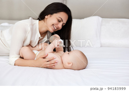 happy mother feeding her newborn baby on the bed happy mother feeding her newborn baby on the bed 94183999