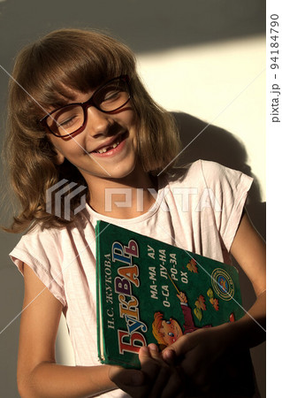 female first grader with textbook smiling broadly laughing 94184790