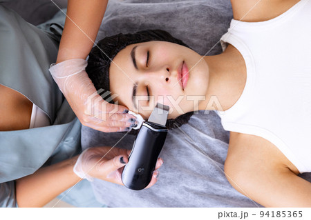Massage, peeling, cleaning. Young beautiful girl during cosmetic procedures in the beautician's office. Spa, beauty, wellness, antiaging procedure, cosmetics Massage, peeling, cleaning. Young beautiful girl during cosmetic procedures in the beautician's office. Spa, beauty, wellness, antiaging procedure, cosmetics 94185365