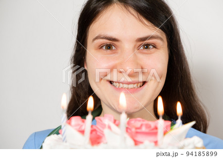 A woman doctor in a blue uniform holds a birthday cake with candles and smiles. 94185899