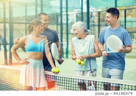Happy players with rackets for padel talking on outdoor tennis court 94186079