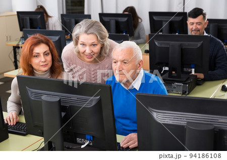 Elderly people working together on computer 94186108