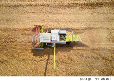 Harvest season, Aerial view of harvesting combine working in agricultural field 94186361