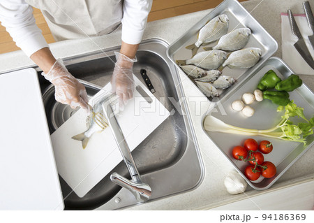 キッチンで魚を料理する日本人の主婦の手元、釣魚のヘダイを料理する 94186369