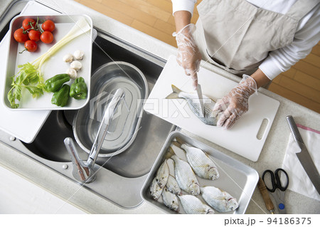 キッチンで魚を料理する日本人の主婦の手元、釣魚のヘダイを料理する 94186375